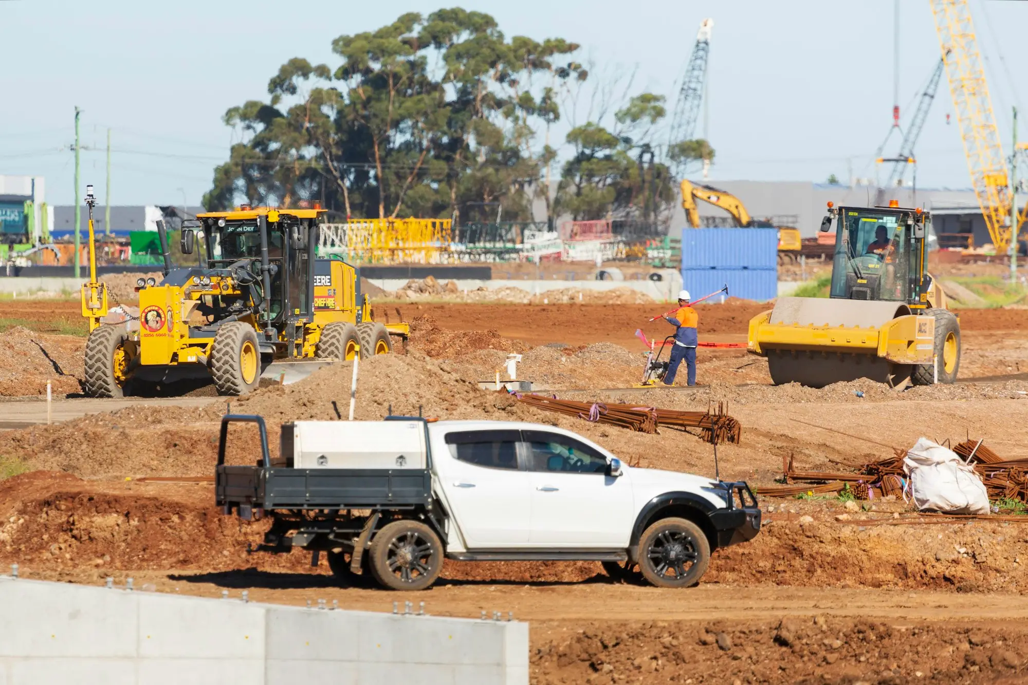 Tradie loading tools into a white ute parked on the left side of a suburban Melbourne street